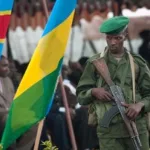 Photo d'illustration : Un militaire rwandais devant les drapeaux Congolais et Rwandais