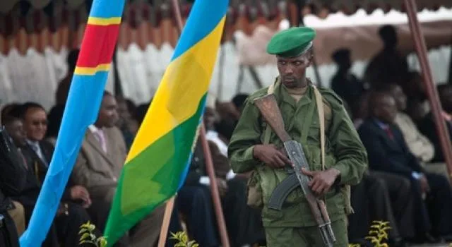 Photo d'illustration : Un militaire rwandais devant les drapeaux Congolais et Rwandais