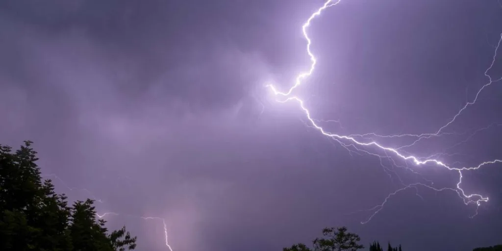 A photograph shows lightning discharges from a thundercloud over trees in Montlouis-sur-Loire, Central France, on May 22, 2022. - Meteo France has placed 21 departments on orange alert for storms due to the heavy temperatures observed since a few days.