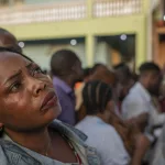 une femme scrute avec intensité la liste des votants dans l'une des stations de vote des élections en République démocratique du Congo en 2023
