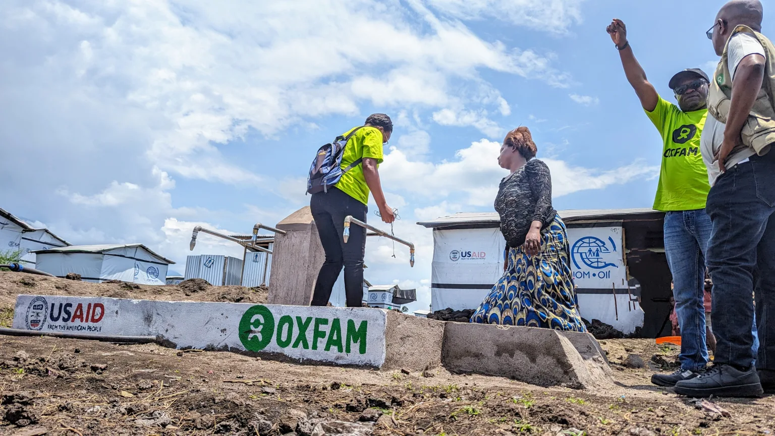 Travailleuse d'OXFAM distribuant de l'eau dans un camp de réfugiés, aidant à fournir des besoins vitaux.