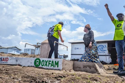 Travailleuse d'OXFAM distribuant de l'eau dans un camp de réfugiés, aidant à fournir des besoins vitaux.